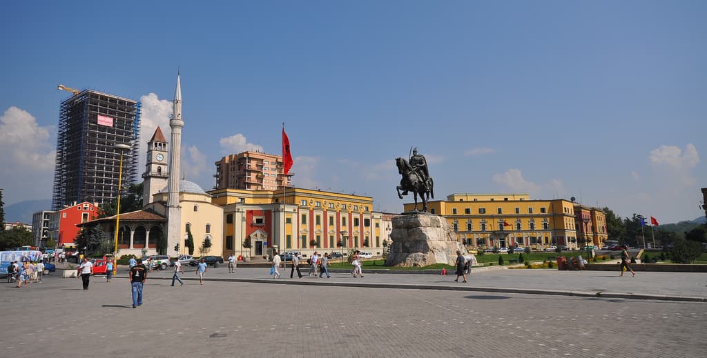 Tirana cityscape with colorful buildings and mountain backdrop.