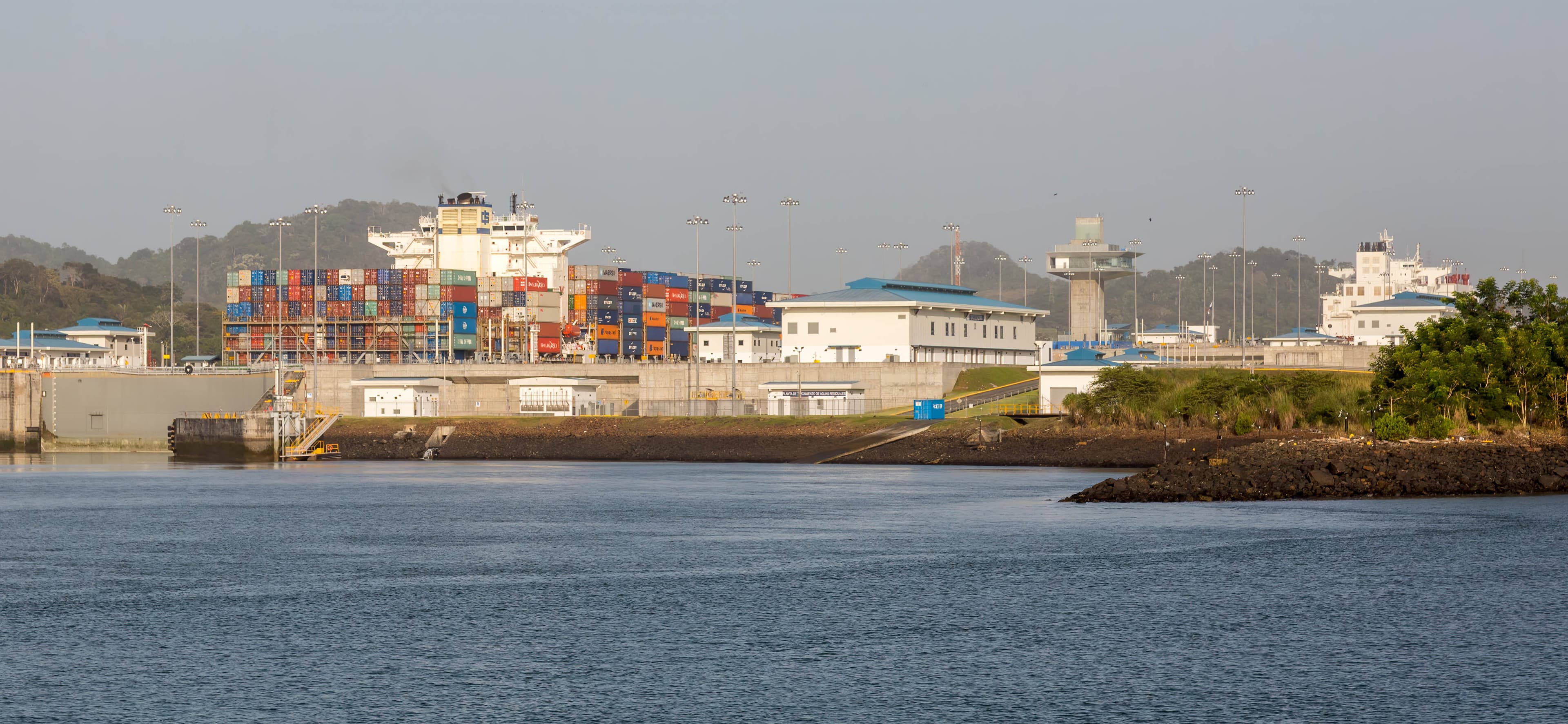 Panama Canal with ships and tropical shoreline.