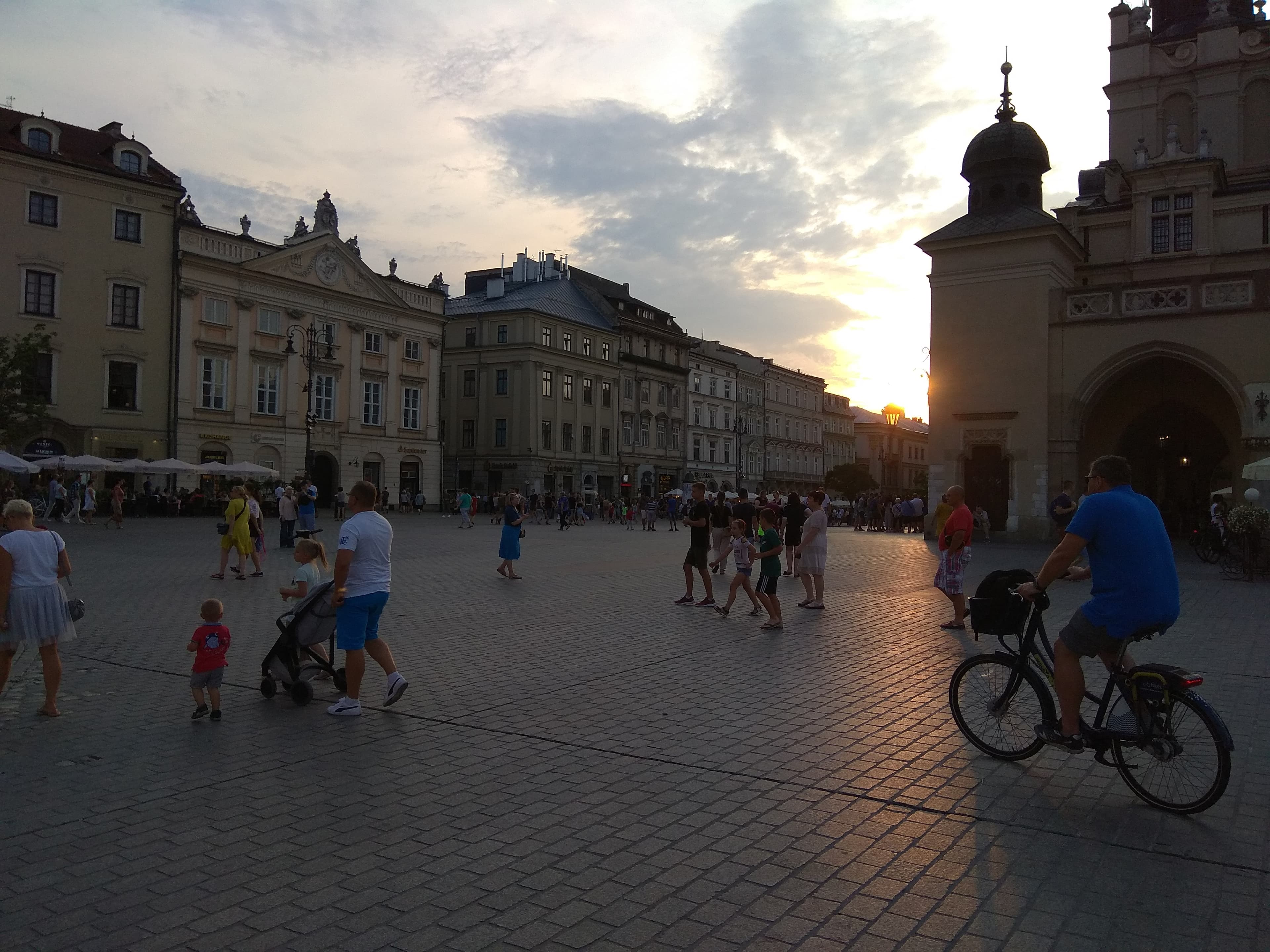 Historic square in Krakow with church towers at sunset.