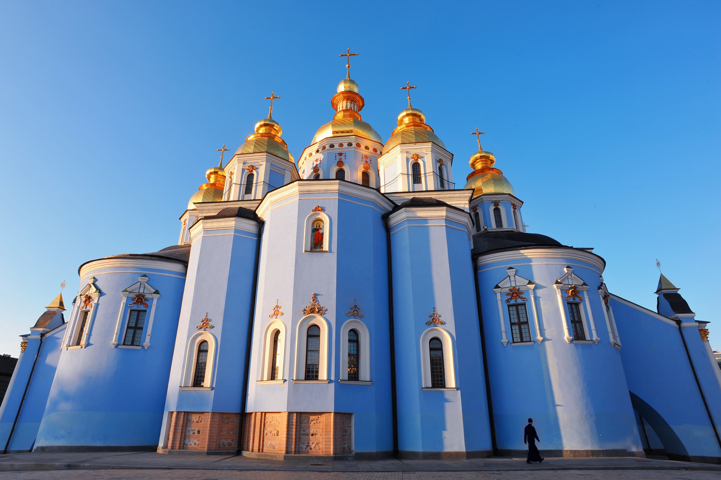 Golden-domed church and Kyiv skyline at sunset.